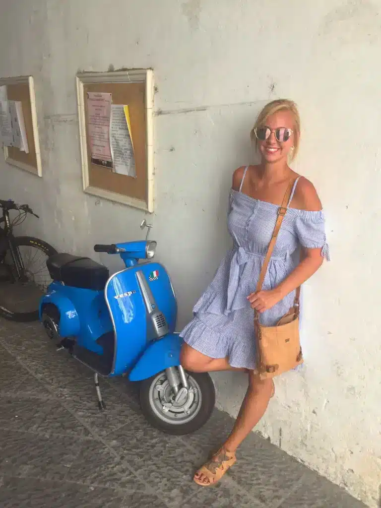 Danielle Nemesio beside a blue Vespa in Sicily