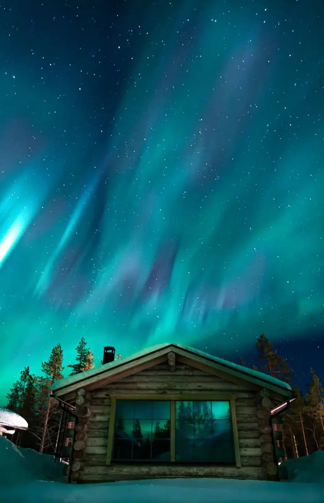 Northern Lights above a wooden cabin in a snowy landscape