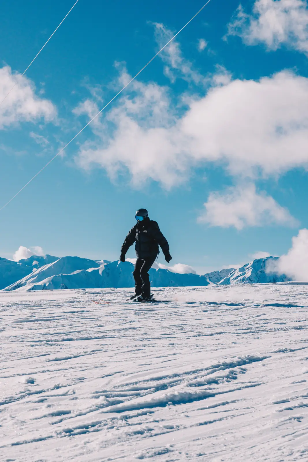 Skier descending a snowy slope beneath a blue sky