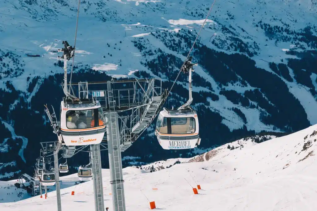 Two ski gondolas travelling above snow-covered mountain slopes