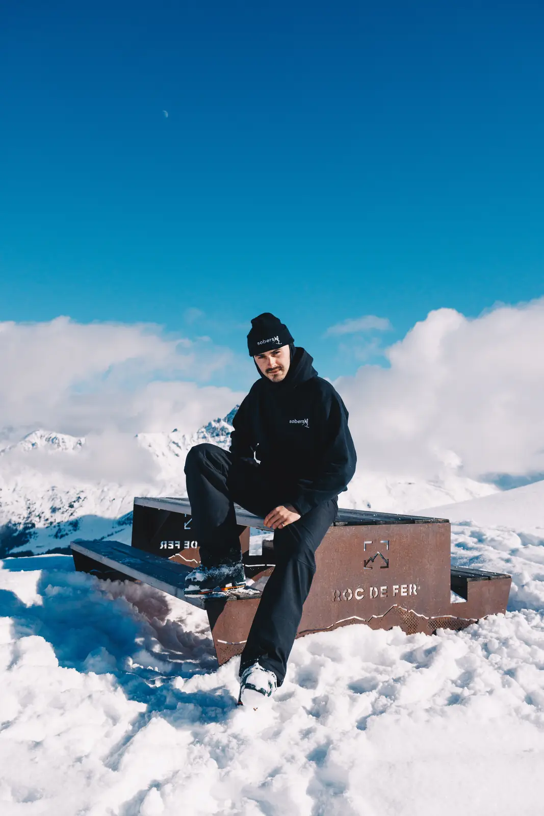 Person seated outdoors with snow-covered mountains behind