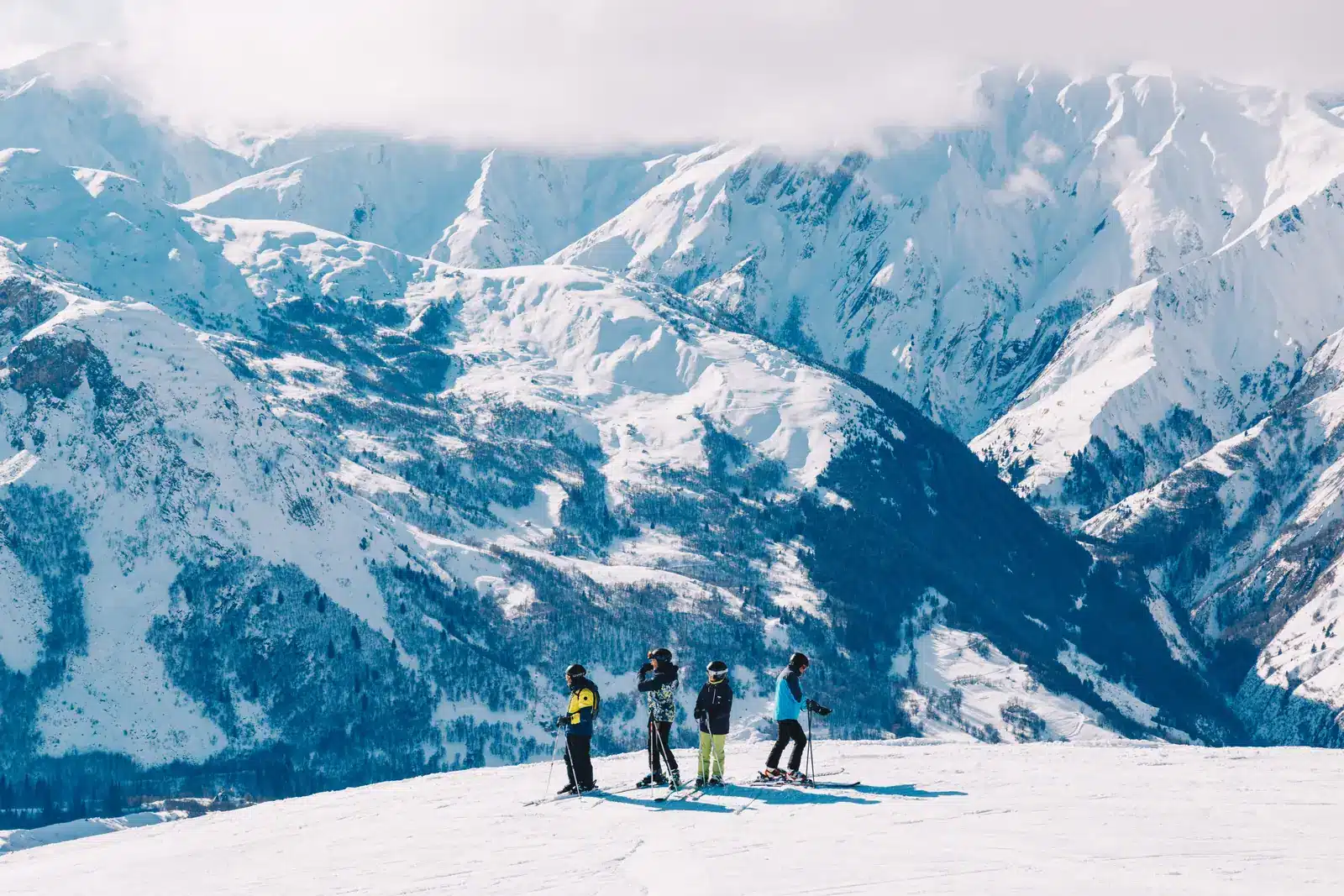 Small group of skiers overlooking a broad snow-covered Alpine valley