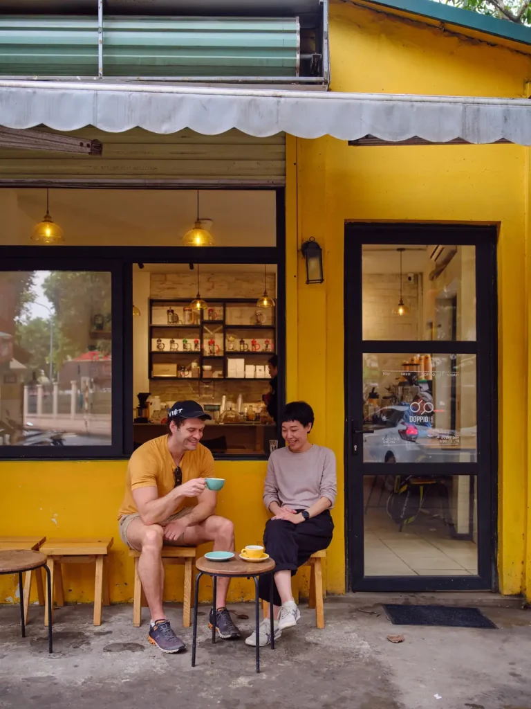 Joshua Zukas sharing coffee outside a yellow-fronted café