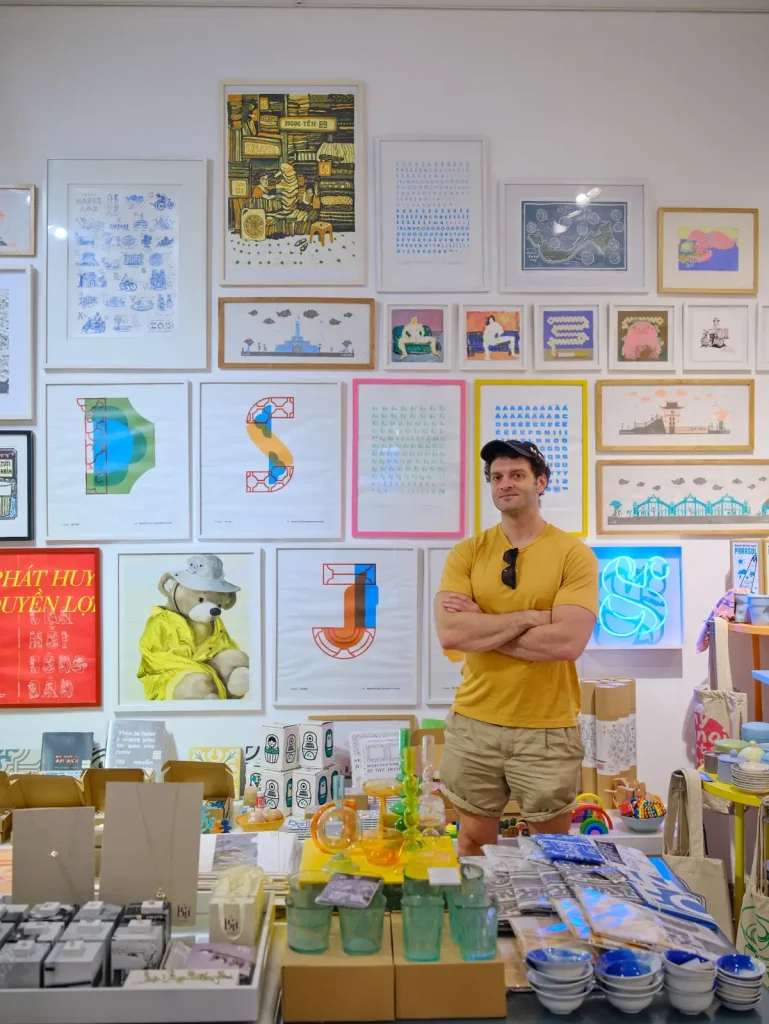 Joshua Zukas in a shop displaying Vietnamese prints and design